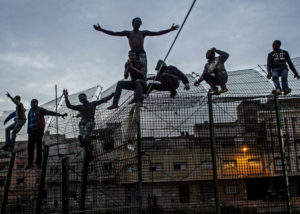 SERGI CÁMARA | Subsaharianos intentando escalar la doble barrera cerca de Beni Enza en Melilla en marzo de 2014, dentro de la exposición <em>Los muros del poder</em>