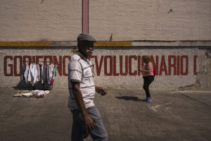 © ADRIANA LOUREIRO FERNÁNDEZ | Un hombre pasa por delante de un puesto de ropa de ocasión en un calle de Caracas, en febrero de 2019