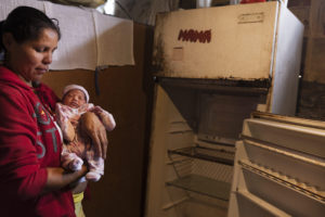 © ANDREA LOUREIRO FERNÁNDEZ | Zuleima Pérez con su bebé delante de una nevera averiada en El Valle, Caracas, en 2017