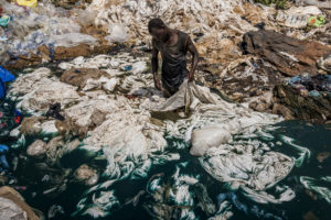 © Frédéric Noy | Un home prop de Katabi, Uganda, neteja amb colorant blau plàstics en un pantà del llac Victòria, el que acabarà contaminant tota l'aigua