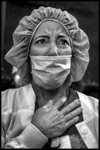 PETER TURNLEY | Erika, enfermera voluntaria brasileña nacionalizada estadounidense, escucha emocionada el himno <em>America the beautiful</em> delante del hospital Lenox Hill