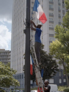 ARCHIVE | Une image symbolique de <em>Nous</em>, avec des drapeaux français qui président une cité de la périphérie parisien