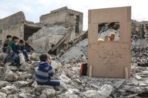 ANAS ALKHARBOUTLI/DPA/UNOCHA | Des enfants syriens regardent un spectacle de marionnettes au milieu des runes dans la ville de Saraqib, dans la province du nord-ouest d'Idleb, en mars 2019