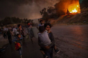 ANGELOS TZORTZINIS/AFP | Des réfugiés dans le camp de Moria, sur l'île grecque de Lesbos, fuyant les flammes, le 9 septembre 2020