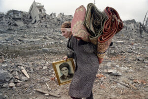 ÉRIC BOUVET | Une femme traverse la place Minutka détruite, à l'entrée sud de Grozny, en février 2000, portant le portrait de son mari, mort lors d'une nouvelle offensive russe sur la Tchetchénie, dans laquelle elle a également perdu ses deux enfants. Bouvet n'a pas pu publier cette photo à l'époque