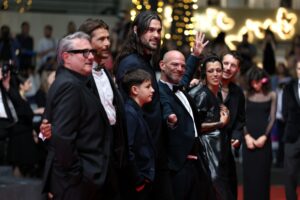 GETTY IMAGES | Una altra imatge de l'equip de <em>Sirât</em>, aquesta vegada amb Sergi López el primer per l'esquerra, el director Óliver Laxe més alt somrient i un dels <em>travellers</em> de la pel·lícula aixecant content la seva mà, en plena catifa vermella a Canes